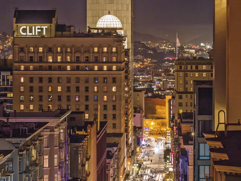 Night-time aerial view showing the exterior of Clift Royal Sonesta hotel in San Francisco, featuring the illuminated Clift sign and the dome on top of the building