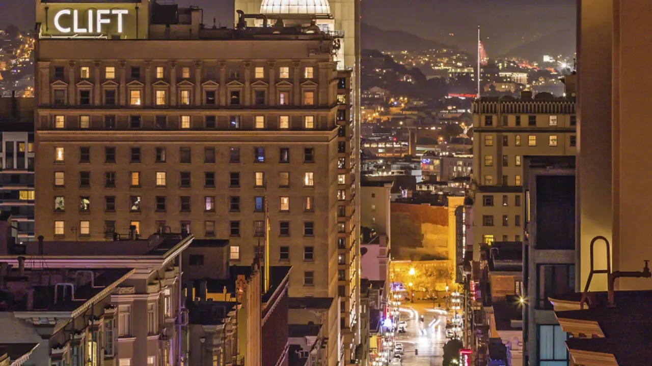 Night-time aerial view showing the exterior of Clift Royal Sonesta hotel in San Francisco, featuring the illuminated Clift sign and the dome on top of the building