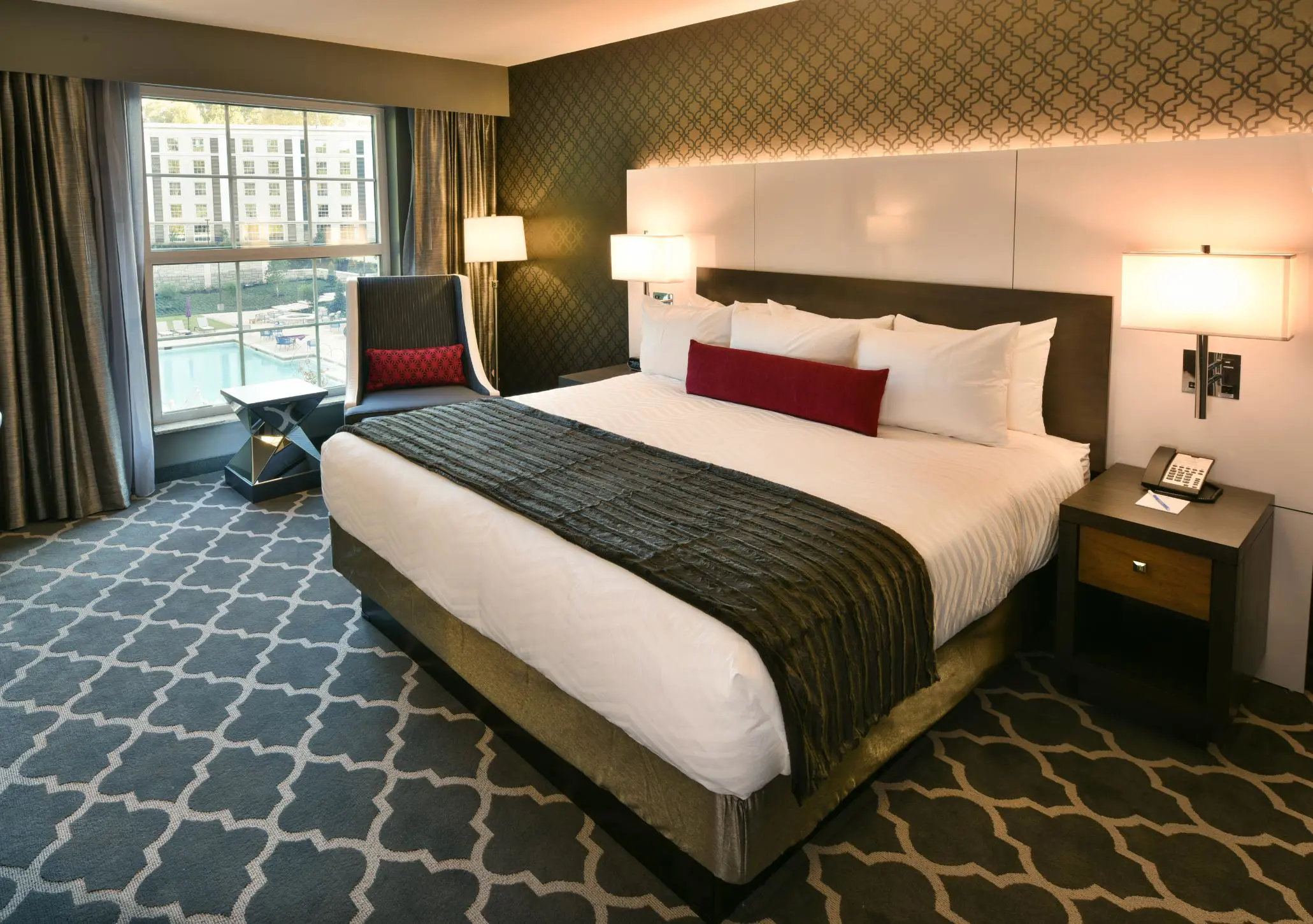 Spacious king bedroom at The Guest House at Graceland, with luxurious bedding, elegant décor, and a view of the pool area