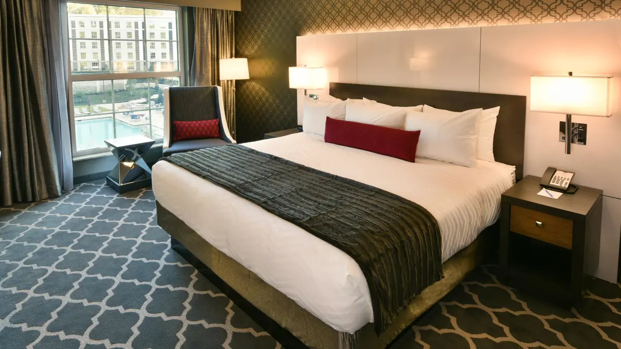 Spacious king bedroom at The Guest House at Graceland, with luxurious bedding, elegant décor, and a view of the pool area