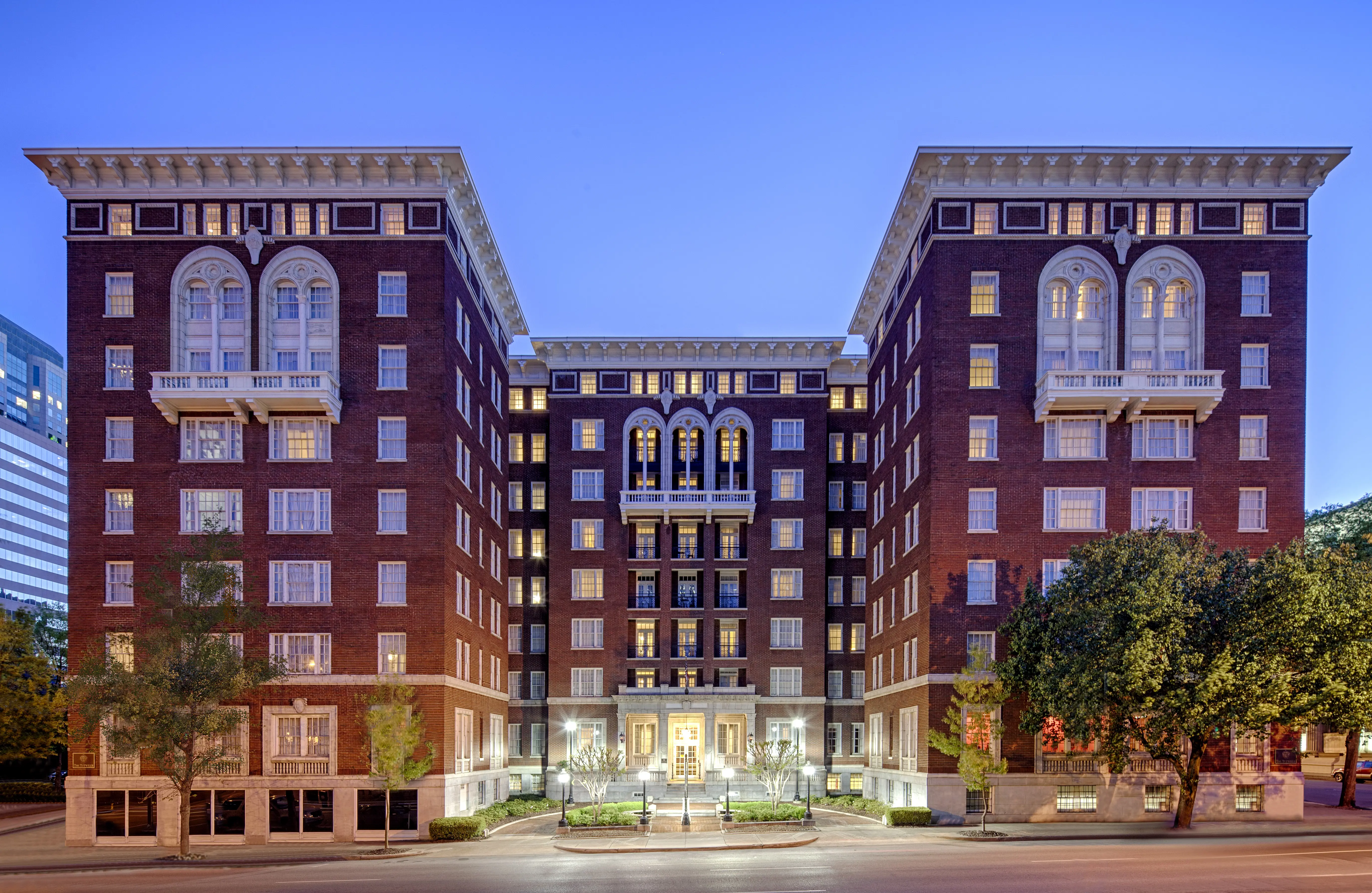 Exterior view of the Hampton Inn and Suites Downtown-Tutwiler, a grand historic red-brick building with classical architecture, lit up at dusk
