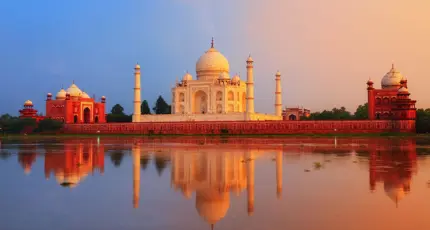 The Taj Mahal in Agra reflected in the calm waters of the Yamuna River at sunset