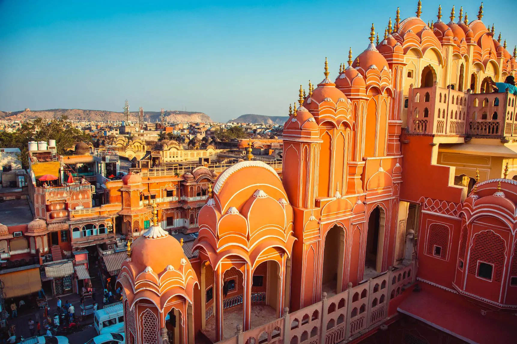 The iconic Hawa Mahal, or Palace of the Winds, in Jaipur, with its pink sandstone façade and latticed windows overlooking the bustling city below in the golden afternoon light