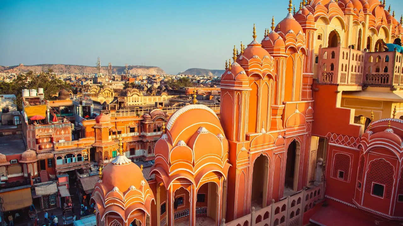 The iconic Hawa Mahal, or Palace of the Winds, in Jaipur, with its pink sandstone façade and latticed windows overlooking the bustling city below in the golden afternoon light