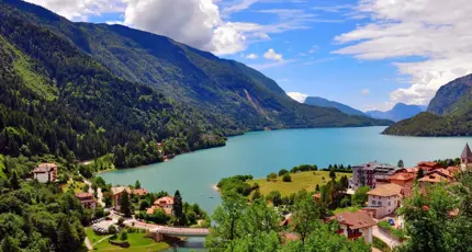 Molveno Lake in Italy, with colourful houses in the foreground and rolling hills alongside the lake
