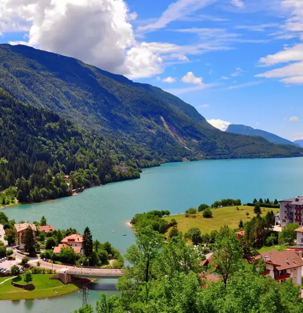 Molveno Lake in Italy, with colourful houses in the foreground and rolling hills alongside the lake