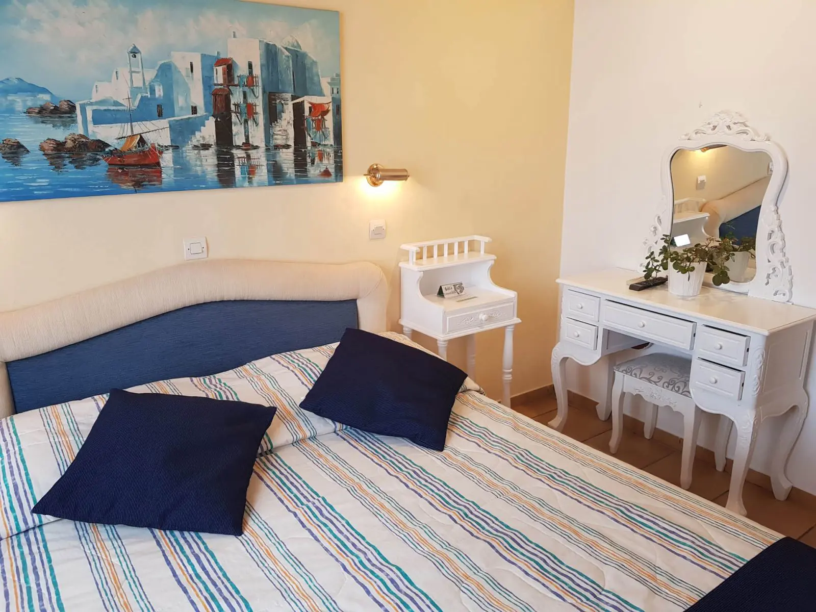 Bright double room at Hotel Ippokampos in Hydra, Greece, featuring a neatly made double bed, whitewashed walls, and traditional wooden furnishings