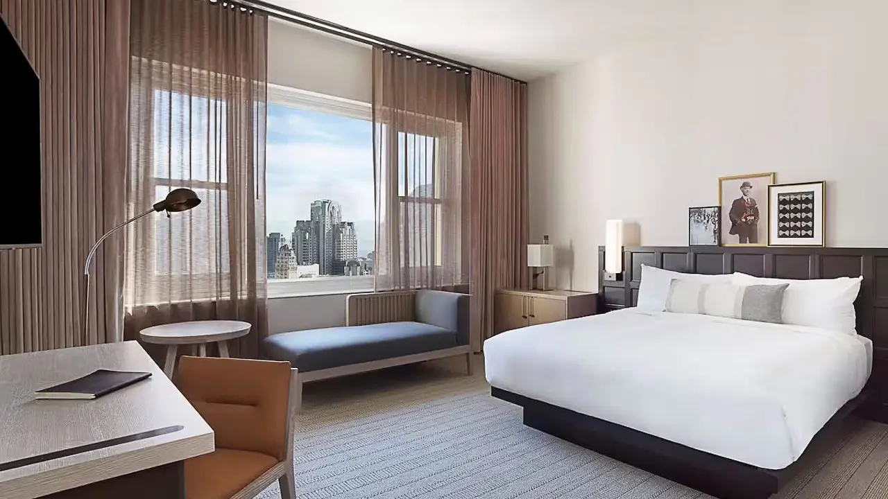 Interior of a king guest room at Clift Royal Sonesta in San Francisco, featuring a large king-sized bed, modern décor, bedside lamps, and a window with city views