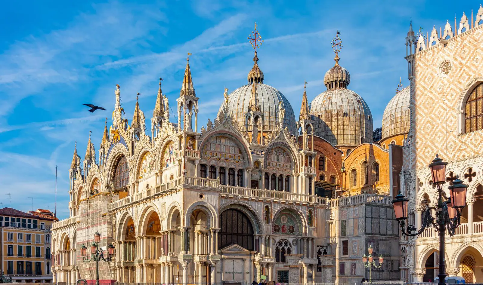 Exterior view of Saint Mark’s Basilica in Venice, Italy, showcasing its ornate façade with domes, arched windows, and detailed mosaics, reflecting Byzantine architectural style