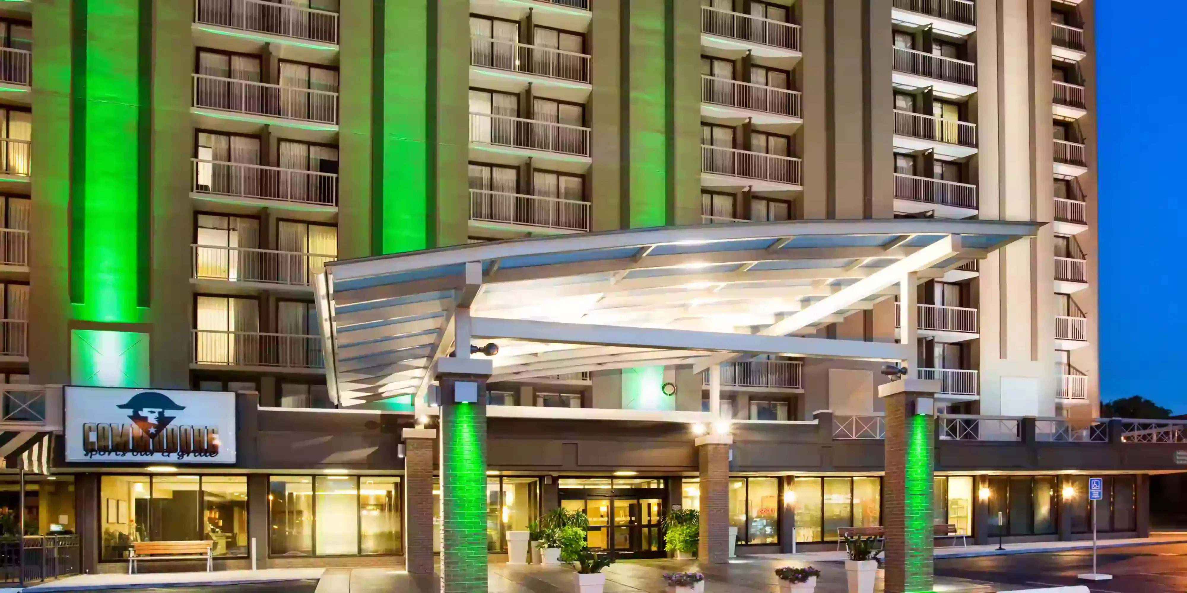 Entrance of the Holiday Inn Nashville Vanderbilt at night, with green-lit pillars and balconies visible on the building