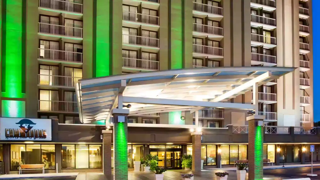 Entrance of the Holiday Inn Nashville Vanderbilt at night, with green-lit pillars and balconies visible on the building