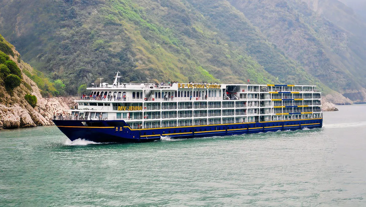 Exterior view of the Victoria Jenna cruise ship sailing through scenic river gorges in China, showcasing its multiple decks and elegant design