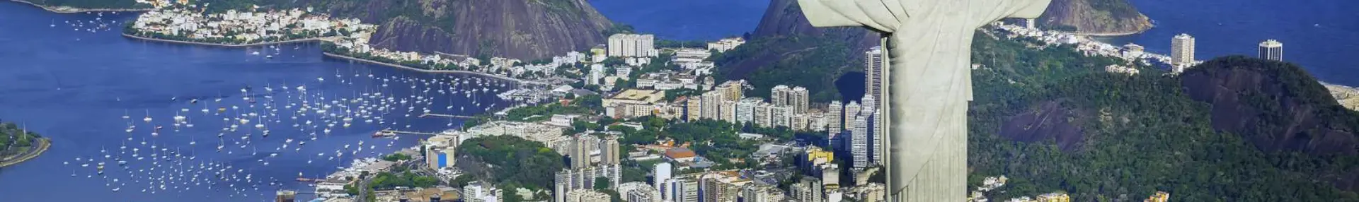 Panoramic view of Rio de Janeiro with Sugarloaf Mountain, the Christ the Redeemer statue, and city buildings along the coastline