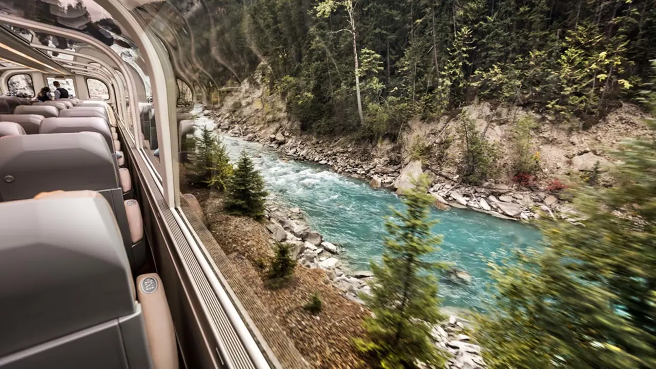 A Rocky Mountaineer train travelling through the Canadian landscape, with sleek carriages and large windows designed for scenic viewing