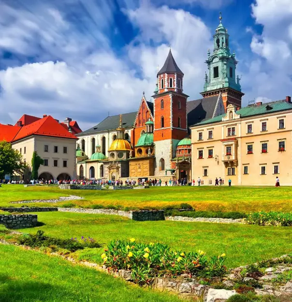 Wawel Castle in Kraków, Poland, showcasing its historic towers and red-brick walls beneath a cloudy blue sky