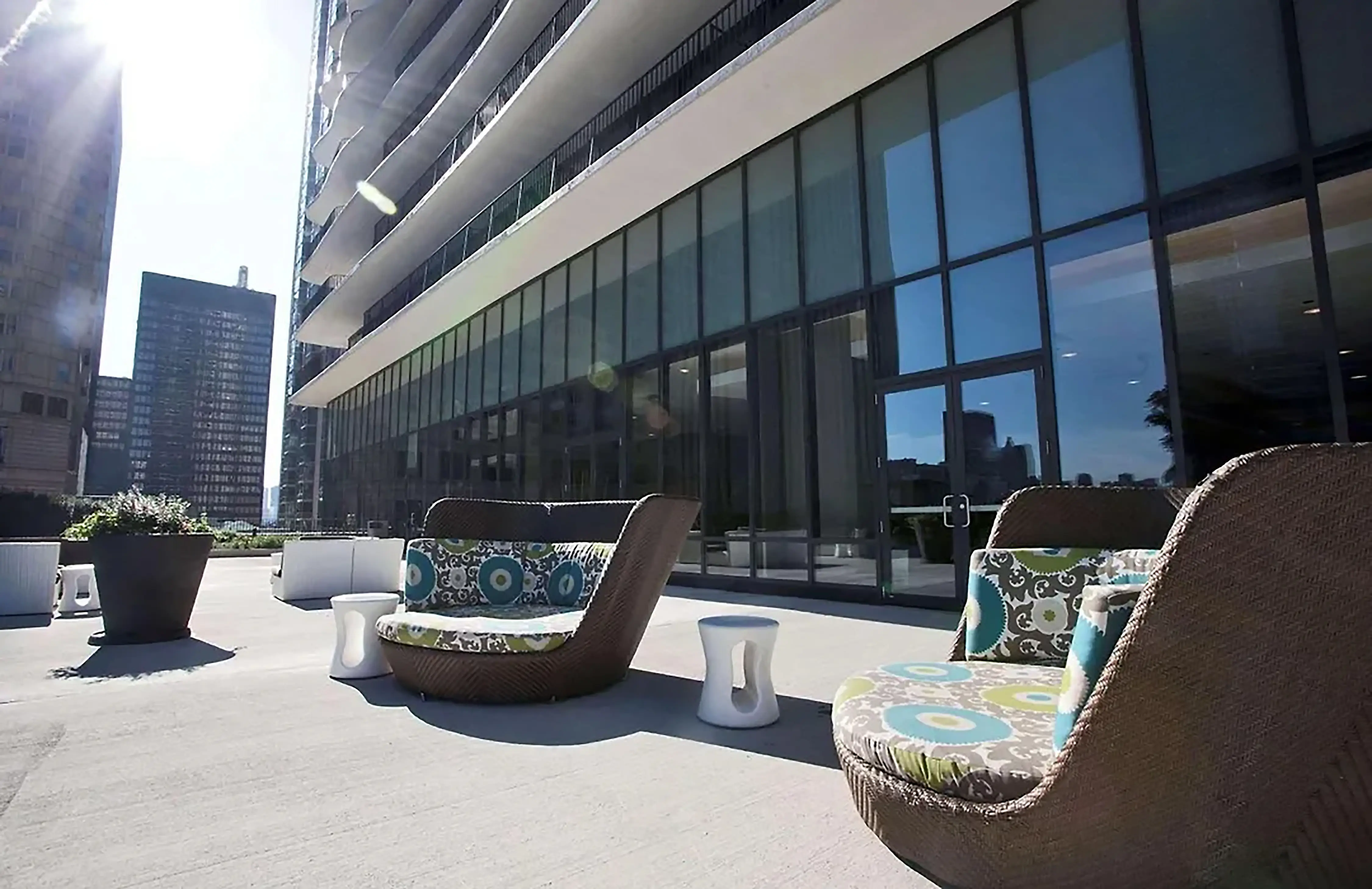 A terrace at Radisson Blu Aqua Hotel, Chicago, featuring modern outdoor seating, sleek design, and views of the hotel’s large glass entrance and surrounding cityscape