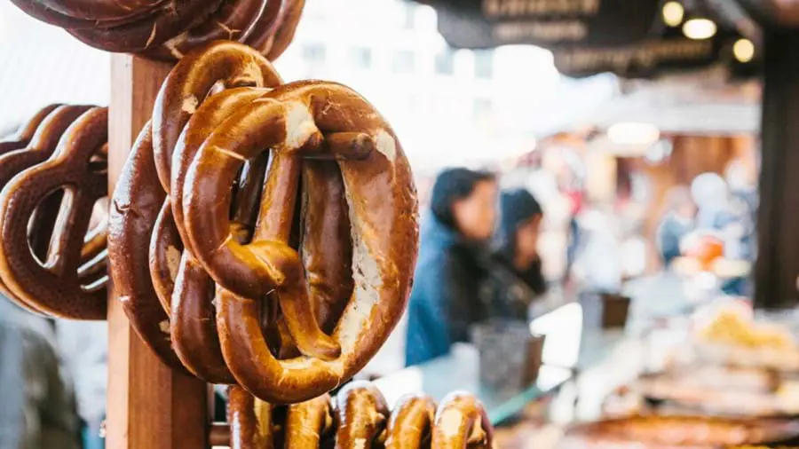 Pretzels hanging on a wooden peg, with blurry people in the background