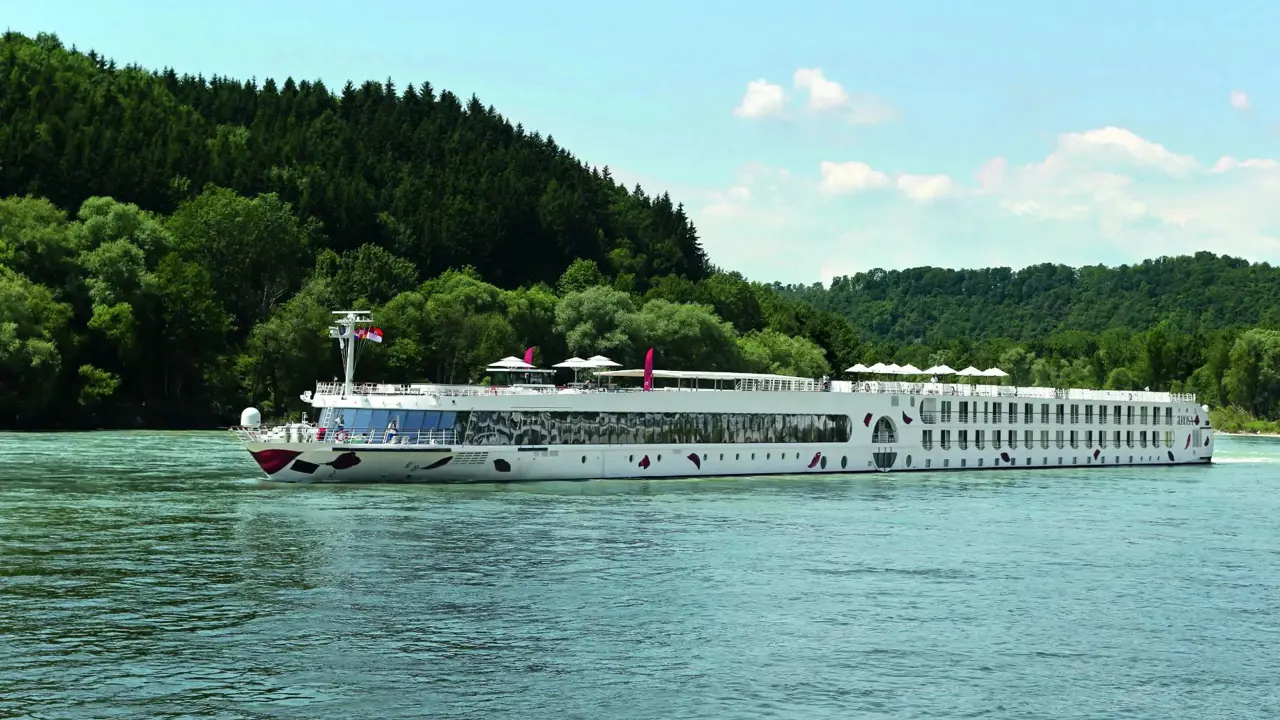 An A-ROSA river cruise ship sailing down a river with trees in the background