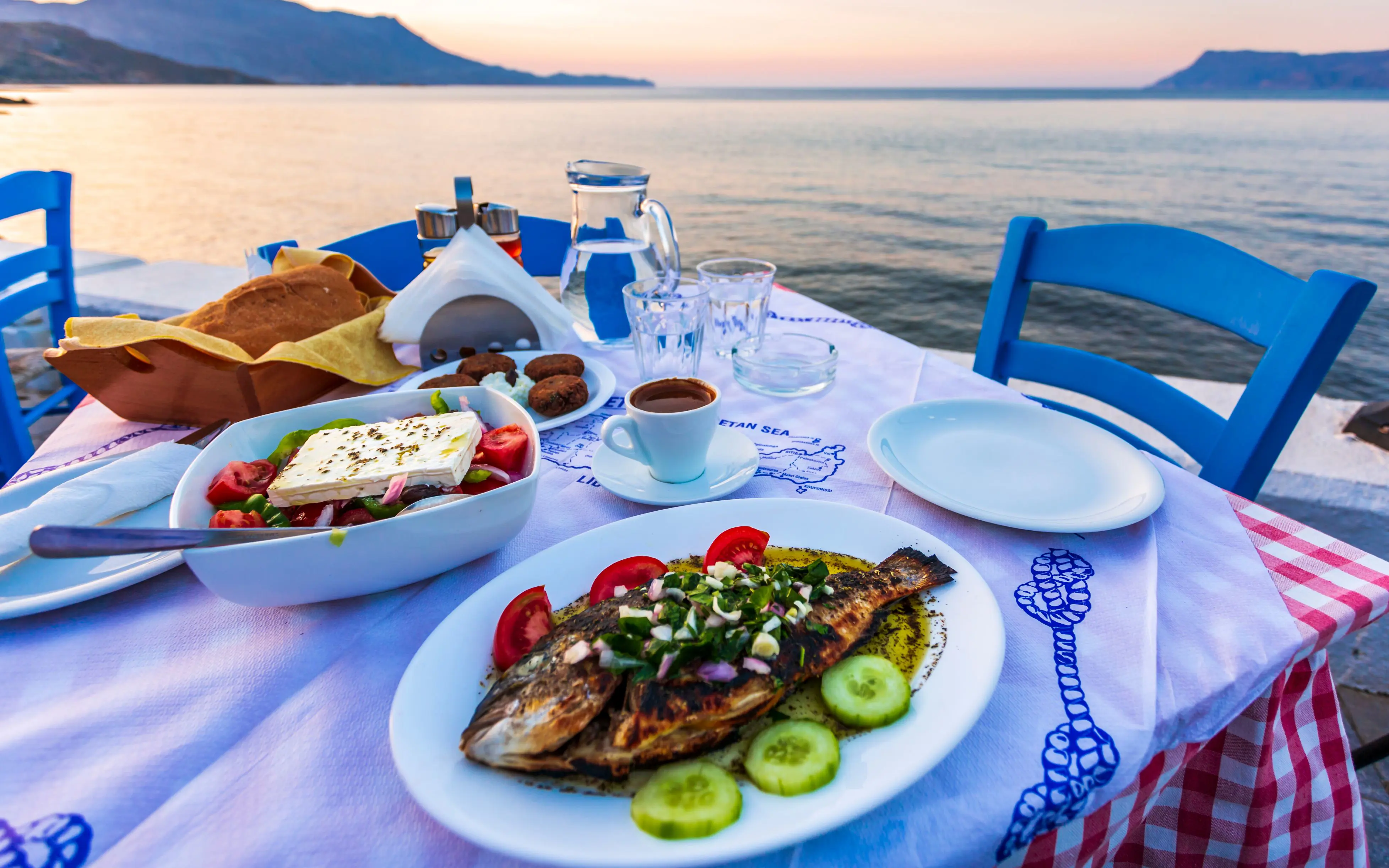 Dinner laid with traditional Cretan Dorada fish with Greek salad, with a view of the sea.