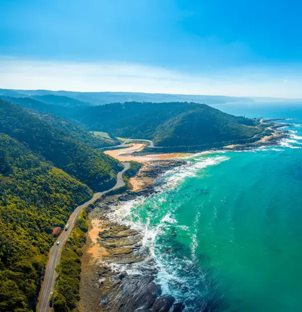 A winding section of the Great Ocean Road in Victoria, Australia, with turquoise waters and rugged cliffs.
