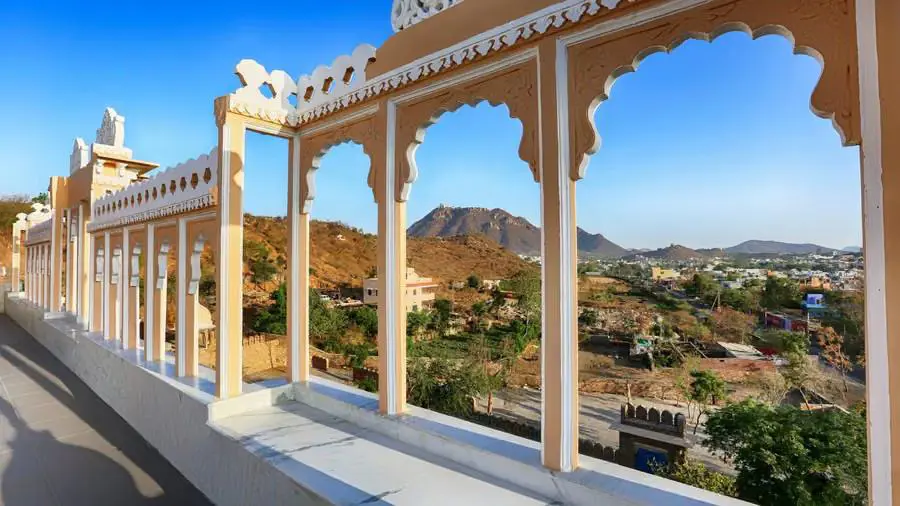 Arched terrace at Fateh Niwas Hotel, Udaipur, framing scenic views of surrounding hills and the city below