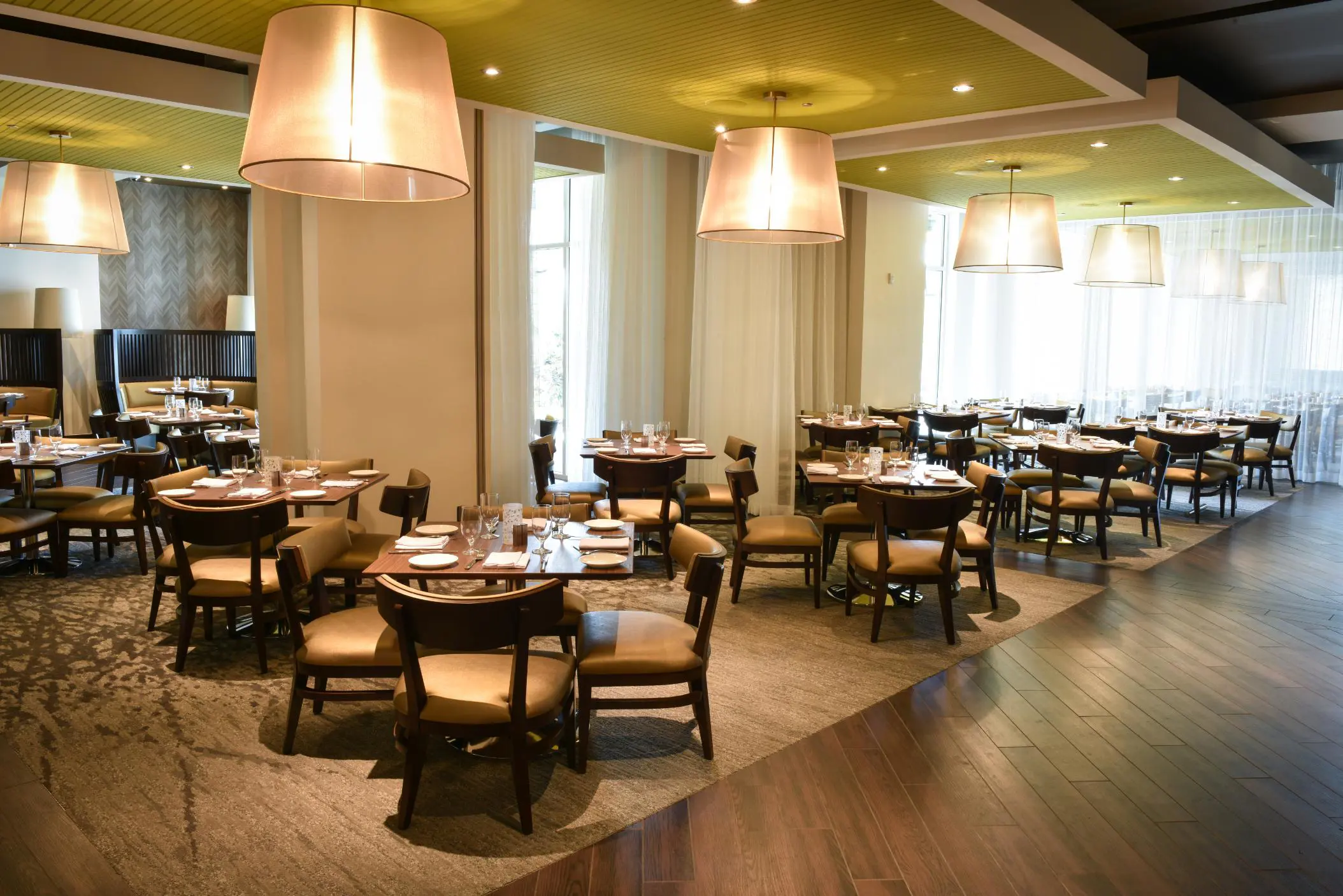Modern restaurant at The Guest House at Graceland in Memphis, Tennessee, with wooden tables, cushioned chairs, soft pendant lighting, and a calm, upscale atmosphere