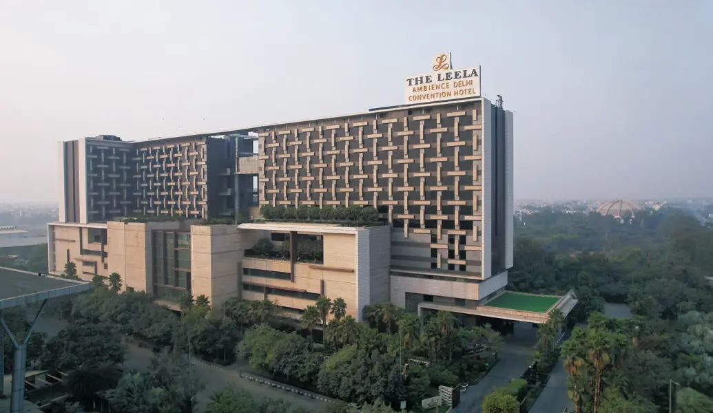 Exterior of the Leela Ambience Convention Hotel in Delhi, showing the modern multi-storey building with glass windows and entrance area