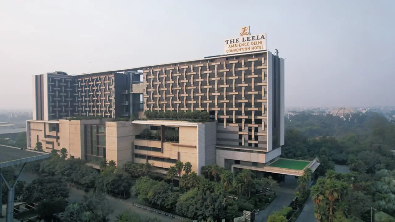 Exterior of the Leela Ambience Convention Hotel in Delhi, showing the modern multi-storey building with glass windows and entrance area
