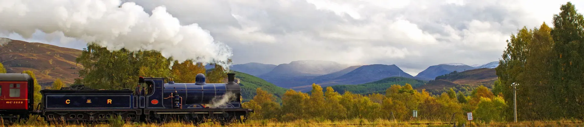 Steam train approaches Kinchurdy Bridge against Cairngorms 