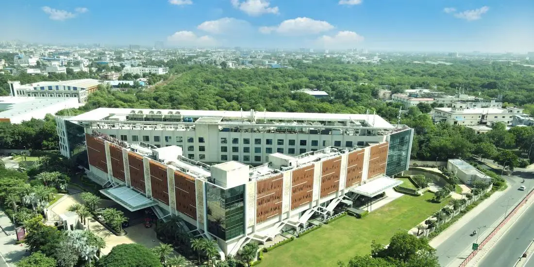 A daytime aerial view of the InterContinental Jaipur surrounded by trees and city buildings