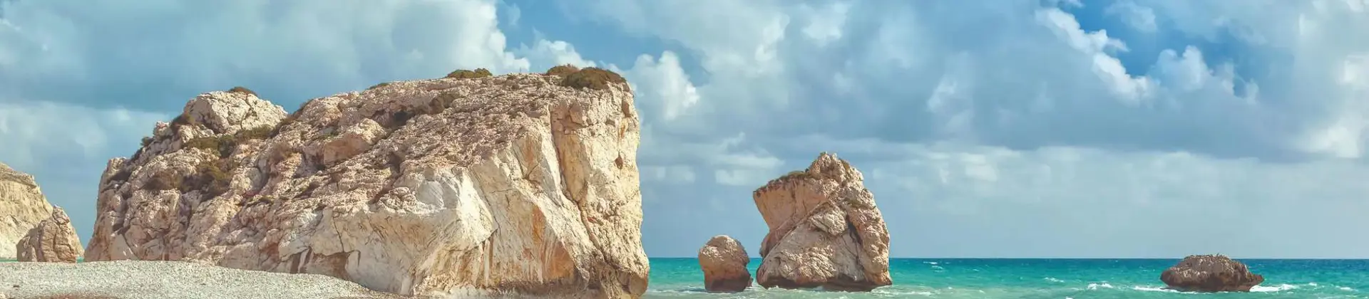 A cloudy day with waves crashing on a pebbled beach near Aphrodite’s Rock in Cyprus