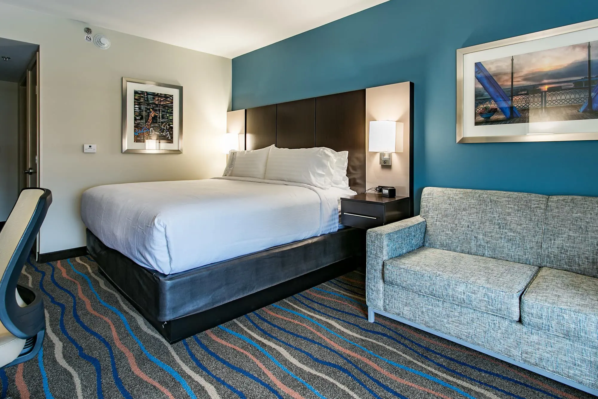 A modern hotel room with king bed and sofa at Holiday Inn and Suites Downtown Chattanooga