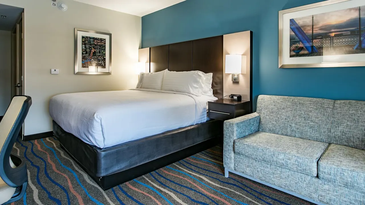A modern hotel room with king bed and sofa at Holiday Inn and Suites Downtown Chattanooga