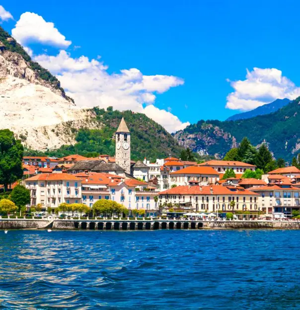 Scenic view of Baveno in Italy, featuring orange-roofed waterfront buildings along Lake Maggiore, framed by surrounding mountains