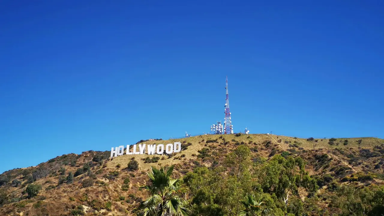 View of the iconic Hollywood sign on a hillside in Los Angeles, with clear blue sky and surrounding greenery