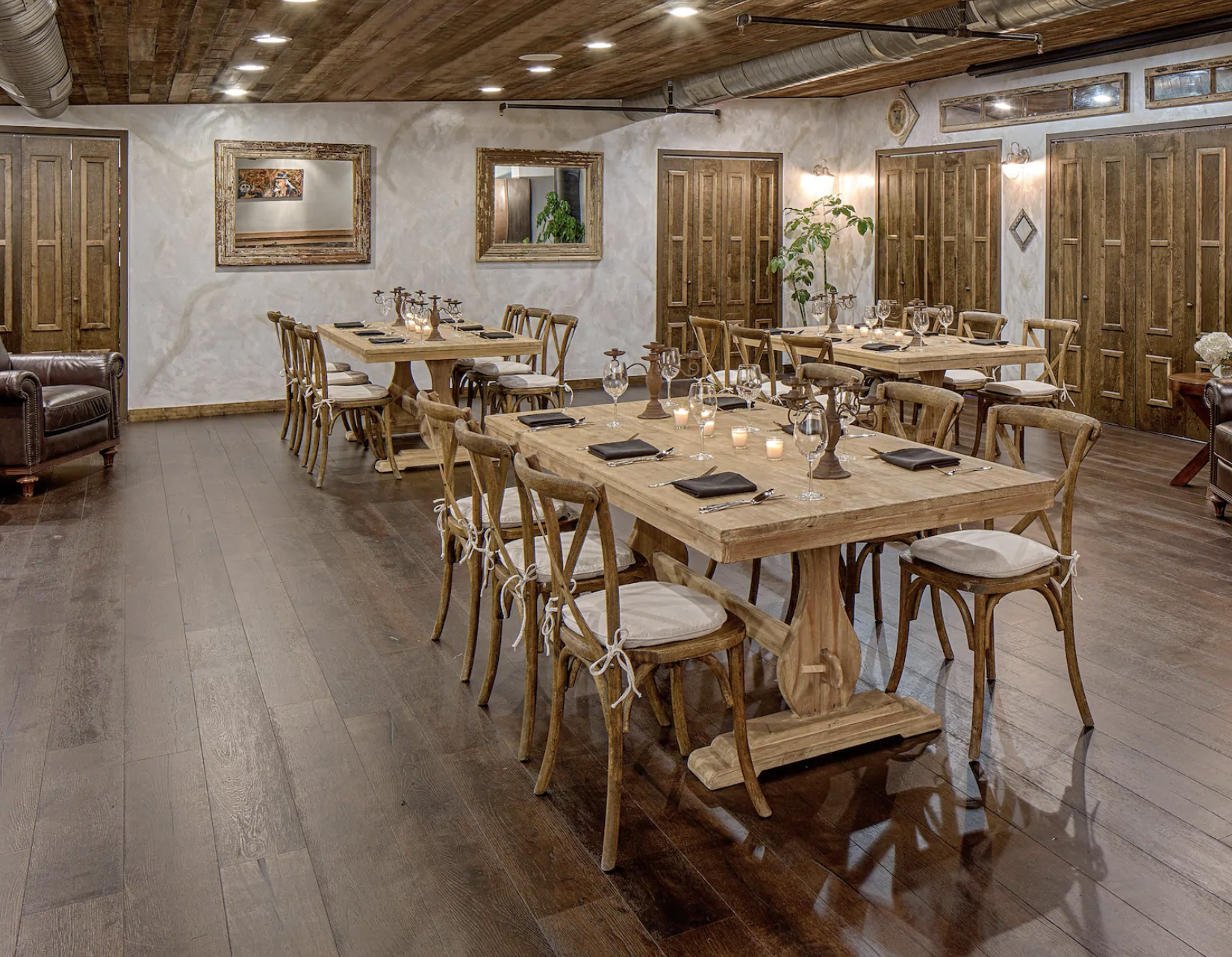 Cosy dining room with rustic wooden tables and chairs, set with candles and glassware, featuring wooden floors and a French country style at the Wyndham French Quarter