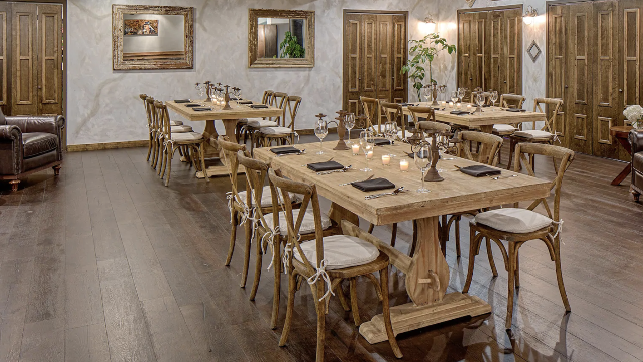 Cosy dining room with rustic wooden tables and chairs, set with candles and glassware, featuring wooden floors and a French country style at the Wyndham French Quarter