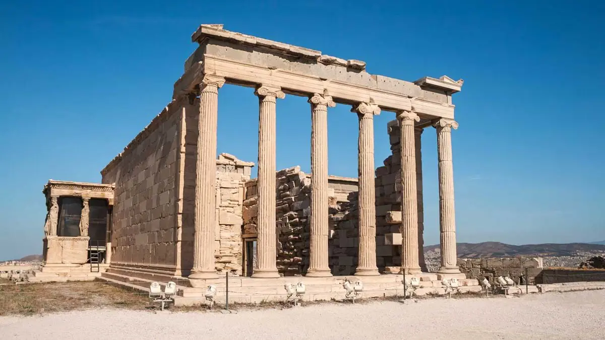 Low angle view of ruins of a building, with pillars at the front. Blue sky behind