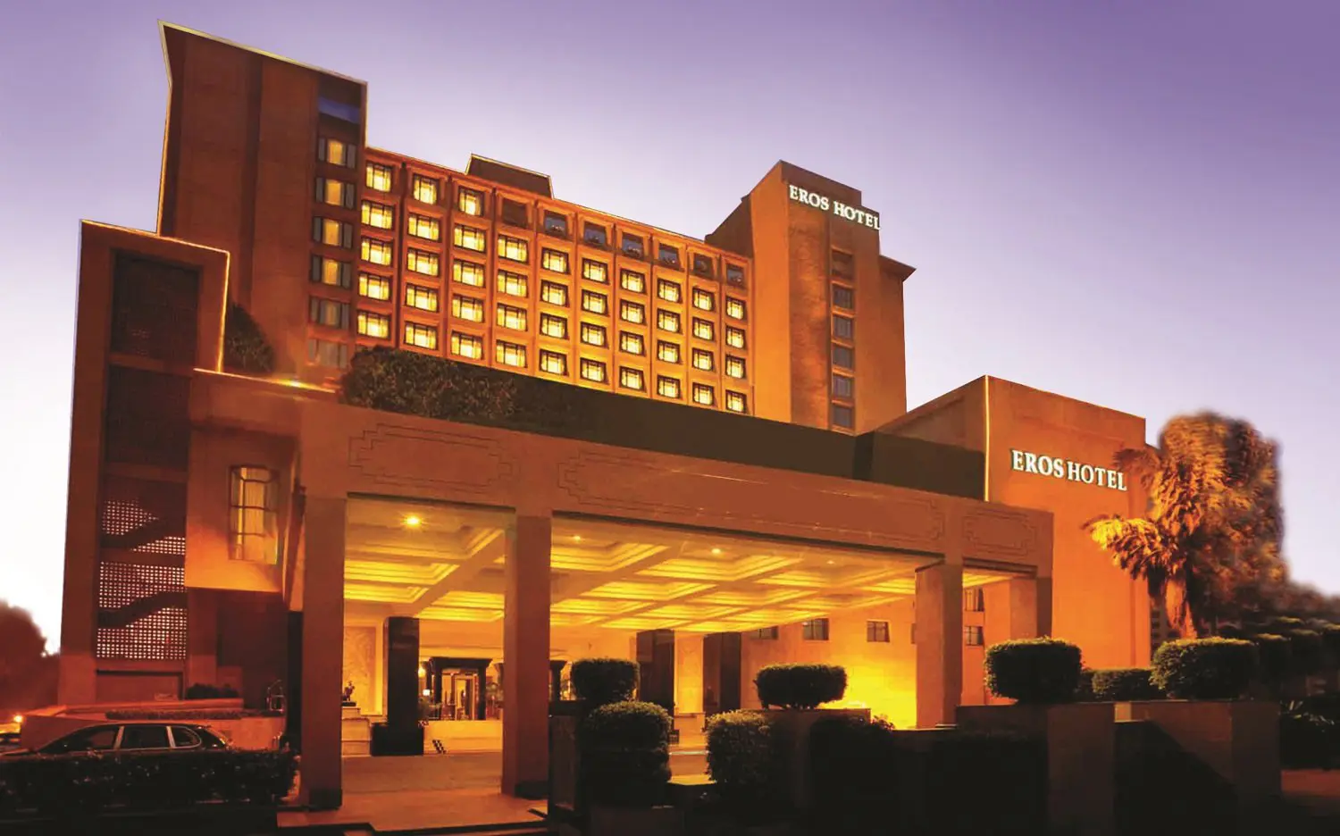 Exterior of the Eros Hotel in New Delhi at dusk, with golden lighting highlighting the grand entrance and tall façade