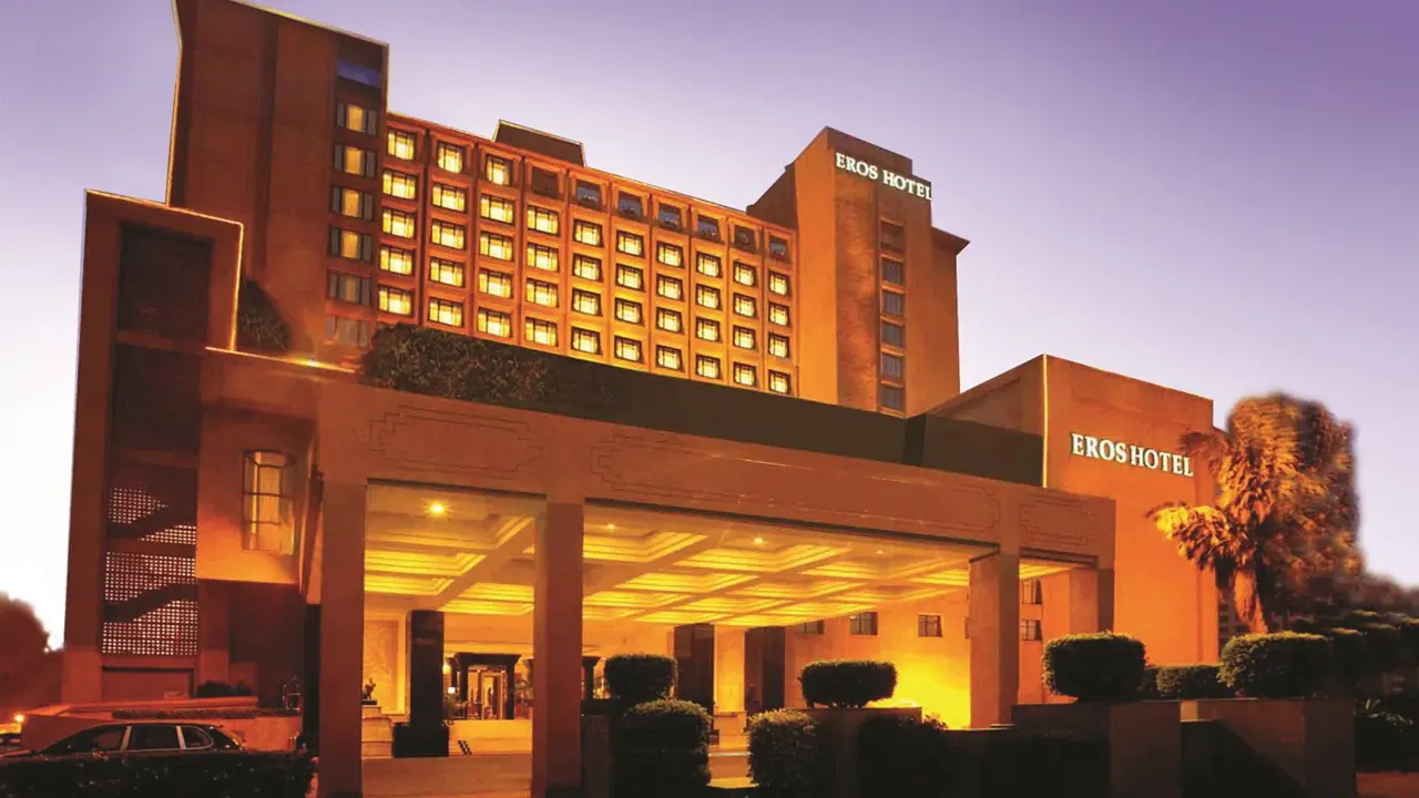 Exterior of the Eros Hotel in New Delhi at dusk, with golden lighting highlighting the grand entrance and tall façade