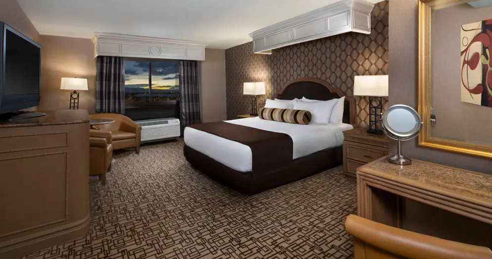 Spacious king room at the Golden Nugget Hotel, Las Vegas, featuring a large bed with white linens, modern furnishings, and warm ambient lighting