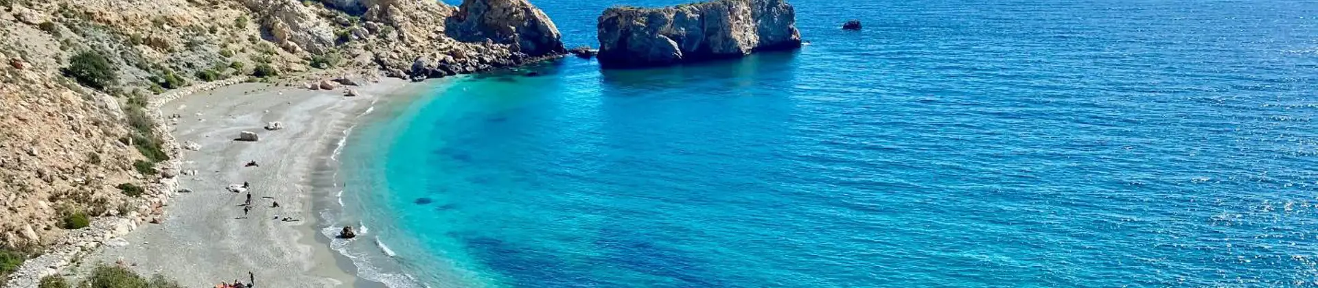 A wide sandy beach along the Costa de la Luz in Andalucía, Spain, with gentle waves lapping the shore under a clear blue sky
