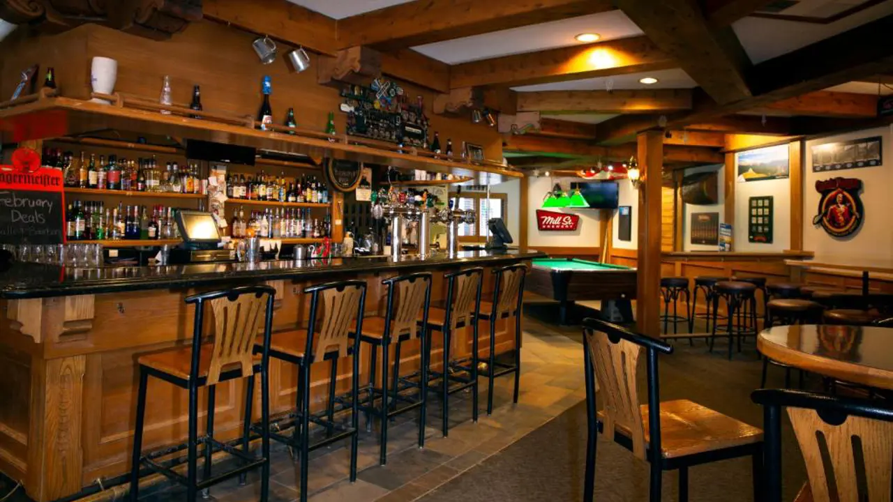 Cosy bar at Whistler's Inn in Jasper, Canada, featuring warm lighting, rustic wood finishes, a pool table and pub-style seating
