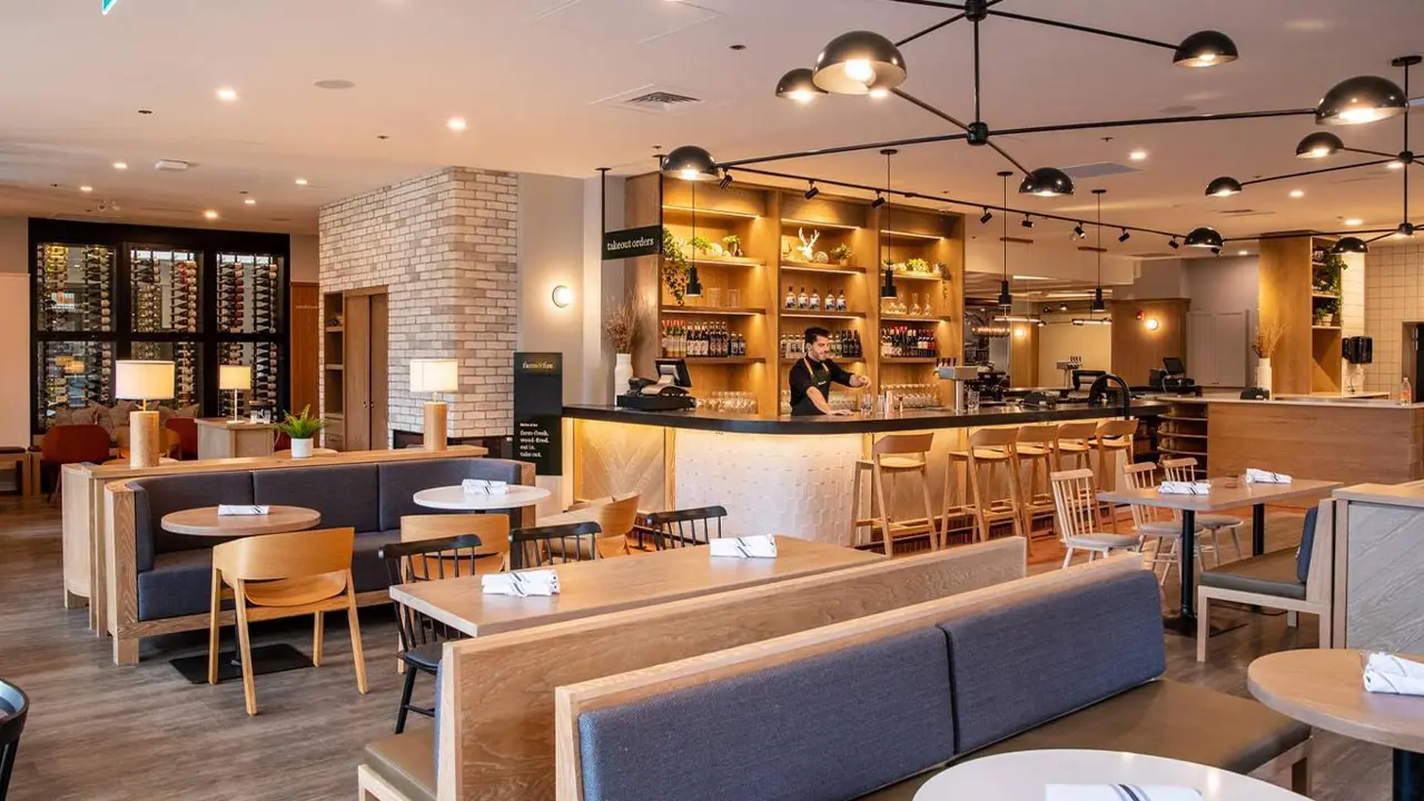 The modern dining area and bar at Elk & Avenue Hotel, Banff, featuring warm wood accents, open shelving, and relaxed seating