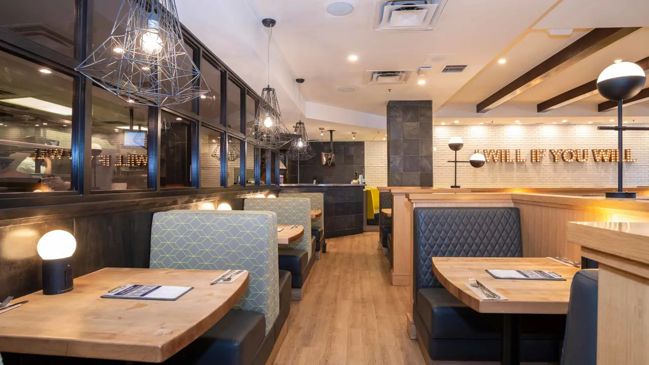 The dining area inside Sandman Signature Calgary Downtown, featuring modern décor, warm lighting, and comfortable seating