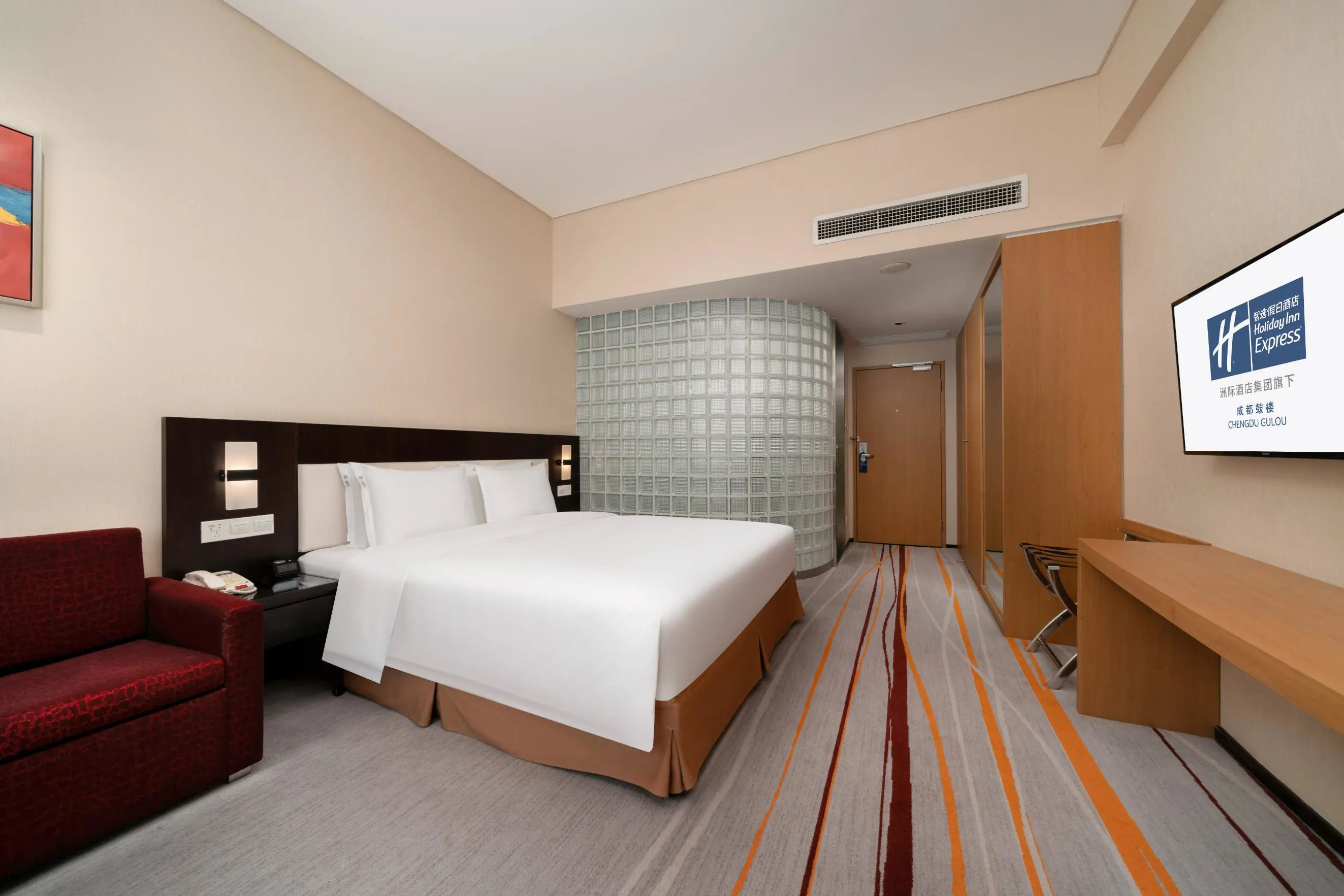 A bright and modern guest room at the Holiday Inn Express Gulou, featuring a comfortable double bed, a sleek desk area, and contemporary décor with warm wood tones and soft lighting