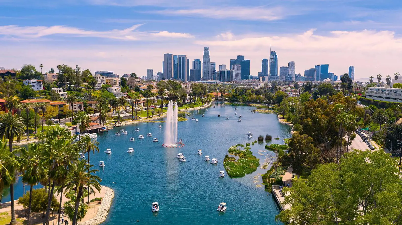 View of Los Angeles with a lake in the foreground, boats on the water, and the city skyline in the background