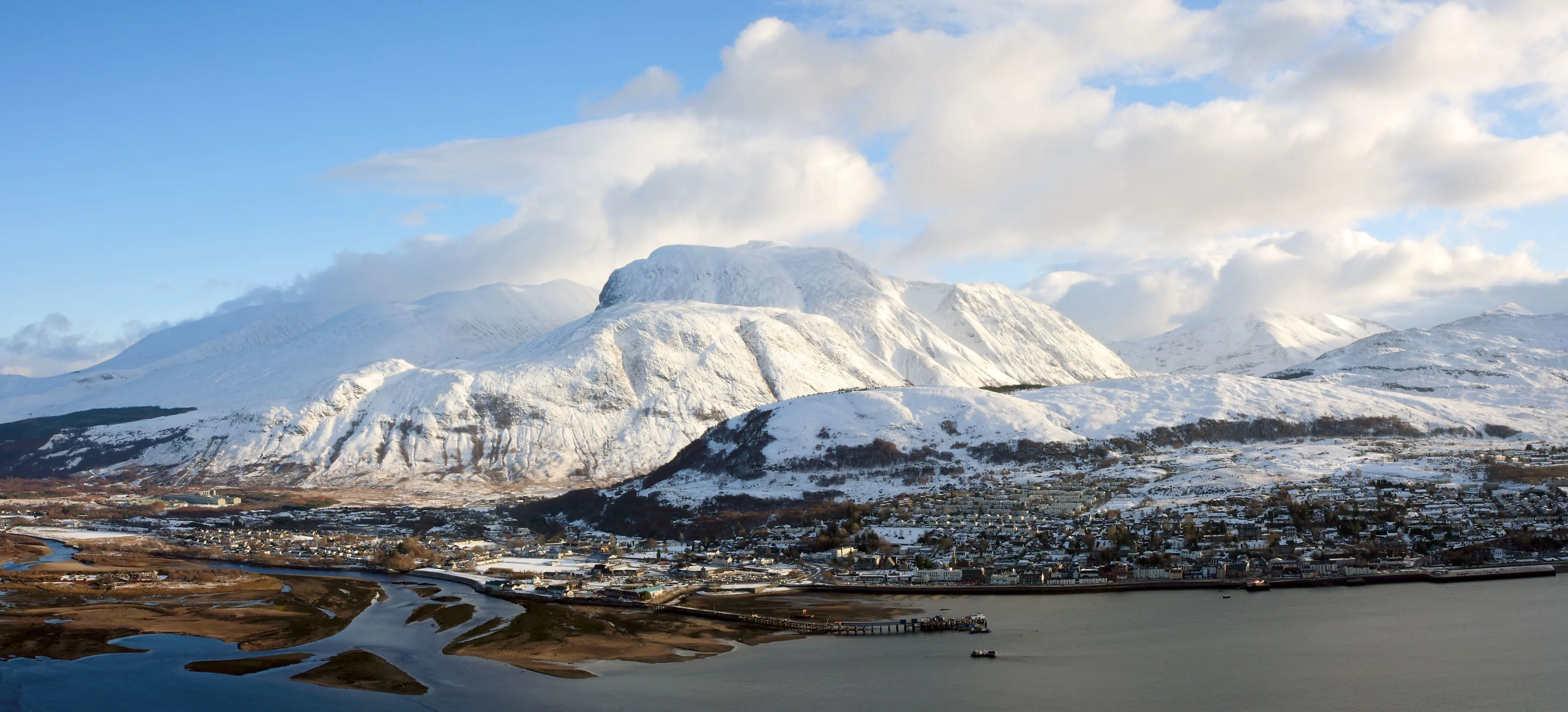 View of Fort William village with snowy Ben Nevis mountain behind 