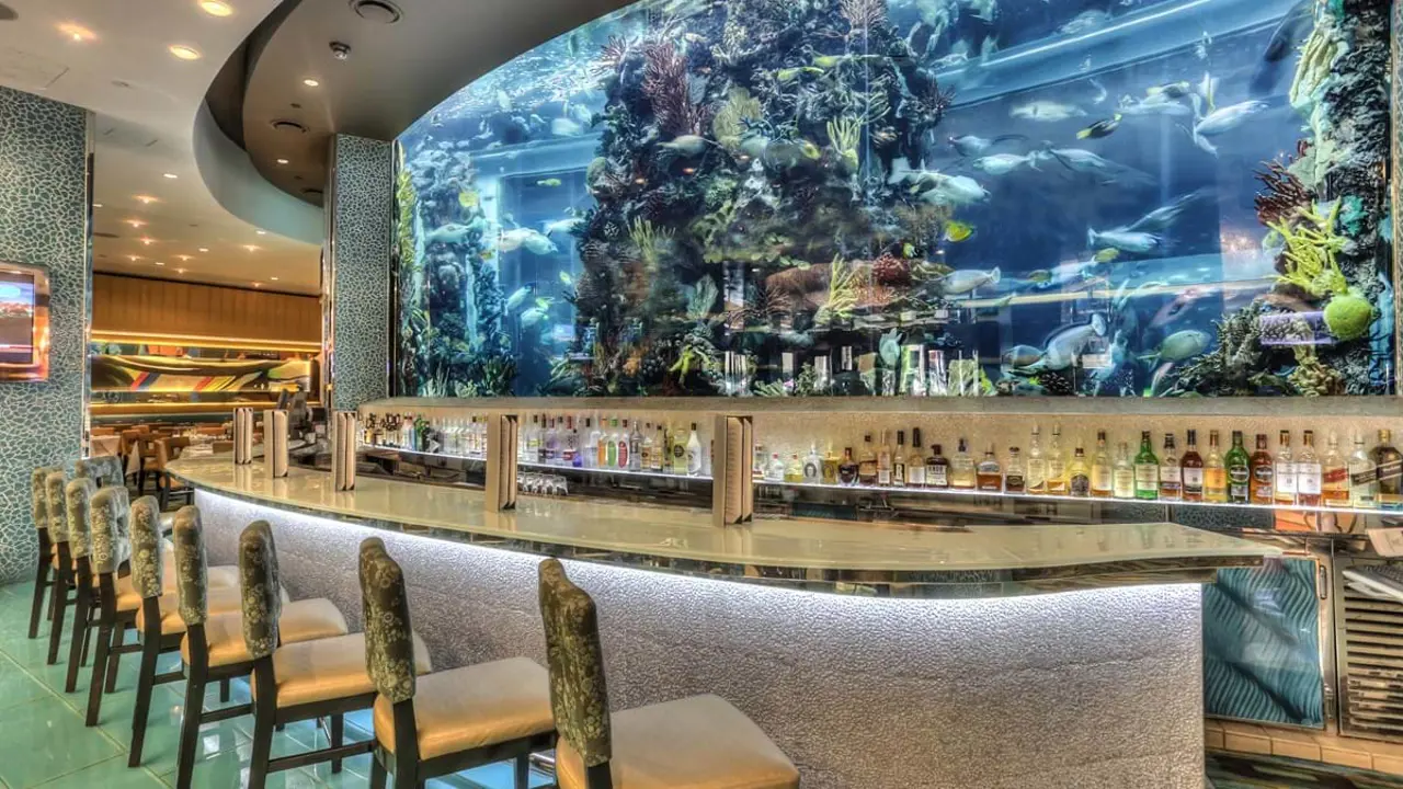 Modern bar at the Golden Nugget Hotel, Las Vegas, with a large fish tank behind the counter showcasing colourful fish, framed by ambient lighting