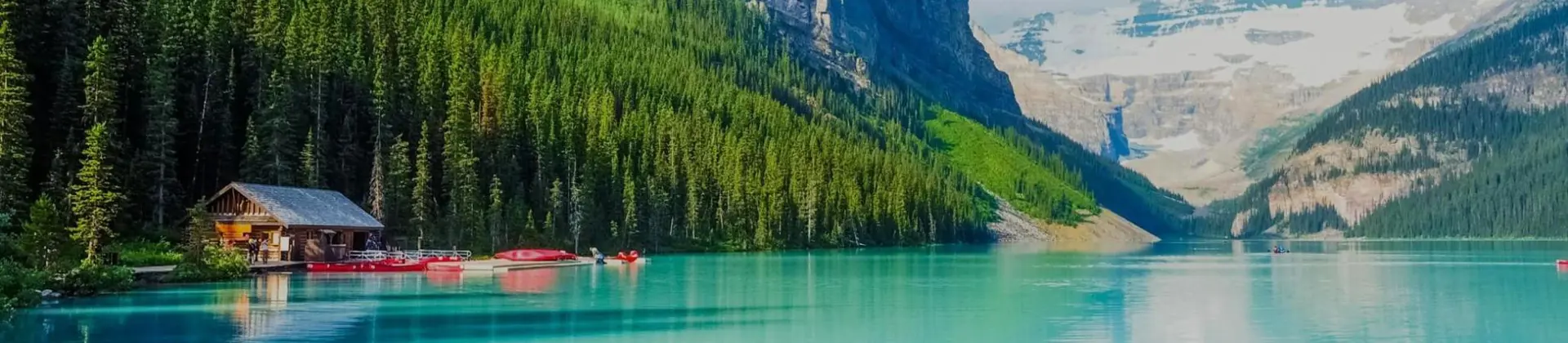 Turquoise waters of Lake Louise surrounded by forested slopes and snow-capped mountains